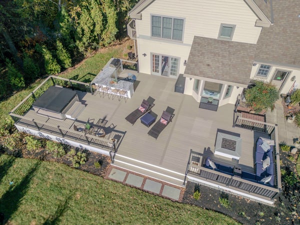 Aerial of the Chadds Ford multi-zone back deck — outdoor kitchen, recessed hot tub, curved sectional, square fire pit — Nature's Call Landscaping