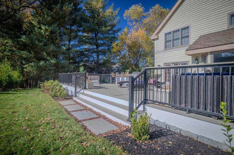 Drone view straight down on the Chadds Ford home and back patio: the composite deck wraps around the back of the tan-siding house with the outdoor kitchen, hot tub, and fire pit zones laid out in a single readable plan