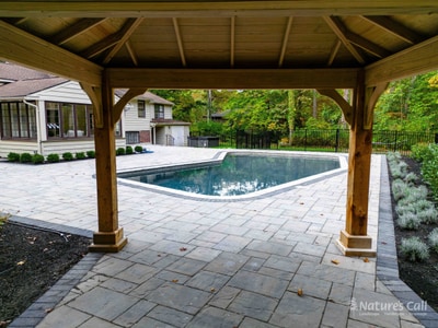 Aerial of a paver pool deck and surround under a timber pavilion — Nature's Call Landscaping hardscaping project