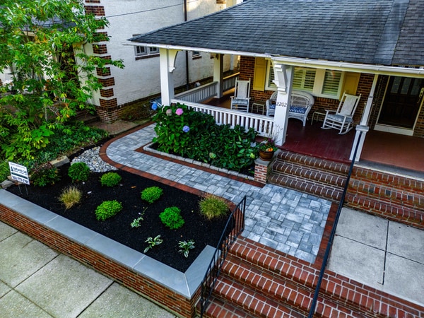 Front entry hardscape with paver walkway, brick header band, brick steps with bluestone caps, and granite-block planter walls. Nature's Call Landscaping in Wilmington.